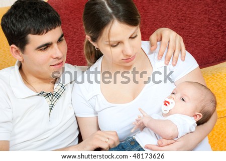happy family home: father, mother and baby sitting on the floor in living room