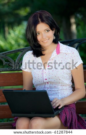 Young beautiful student girl with laptop in the park
