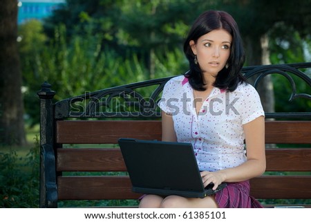 Young beautiful student girl with laptop in the park