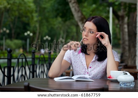 Young beautiful student girl with notepad in the cafe