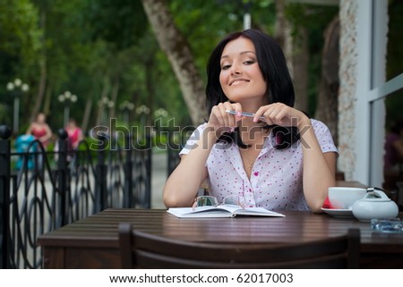 Young beautiful student girl with notepad in the cafe