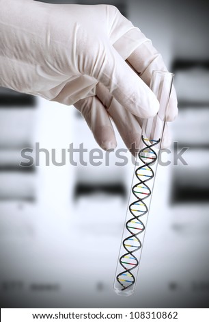 Researchers hand holding test tube with DNA model in front of DNA transparency slide Researchers hand holding test tube with DNA model in front of DNA transparency slide