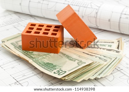 Brick stones with dollar banknotes on home construction blueprints - home or construction financing concept