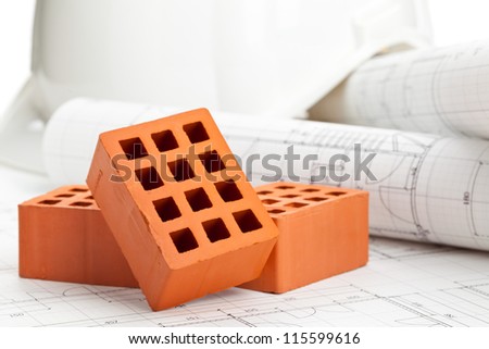 Brick stones on home construction blueprints - house building or construction concept
