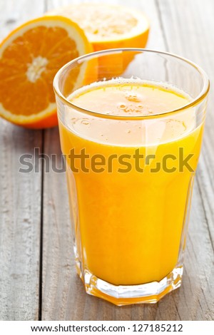 Glass Of Freshly Pressed Orange Juice With Sliced Orange Half On Wooden Table