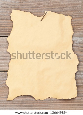 Empty grunge paper with burned edges nailed to wooden wall