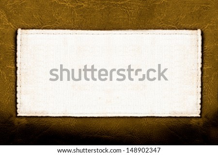 Blank fabric label on leather background close up