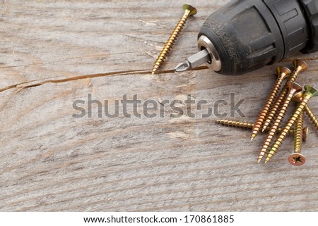 Screws with power drill on old wooden plank