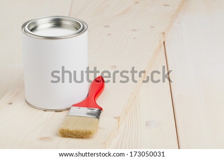 Red paint brush with paint bucket on wooden planks - home renovation or diy concept