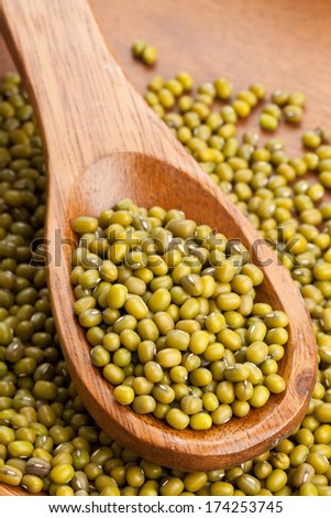 Raw mung beans on wooden spoon in wooden bowl
