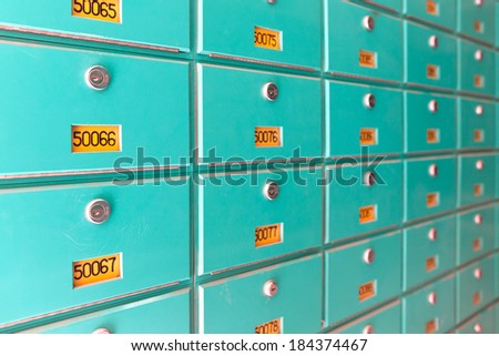 Large number of green metal mailboxes on wall