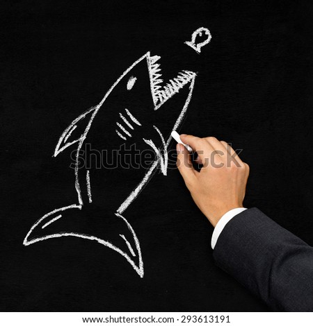 Businessman drawing shark hunting little fish with chalk on blackboard - acquisition, challenge or danger concept