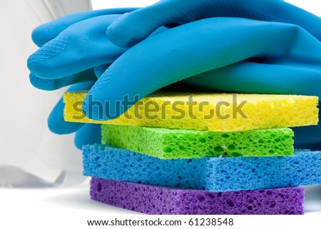 Close up of rubber gloves and sponges over white background