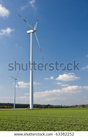 Wind mill in green field with clouds - renewable energy source concept