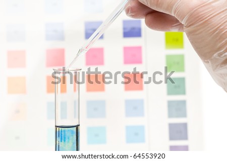 Hand dripping pH indicator into test tube with visible color change in test fluid