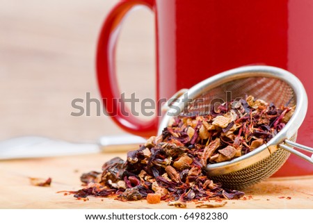Dried fruit tea in tea strainer with cup of tea
