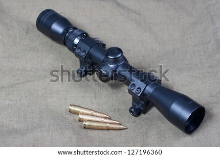 rifle scope and cartridges on khaki background