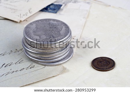 stack of silver dollar coins with copper cent on old paper
