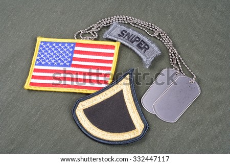 KIEV, UKRAINE - August 21, 2015.  US ARMY Private First Class rank patch, sniper tab, flag patch and dog tag on olive green uniform
