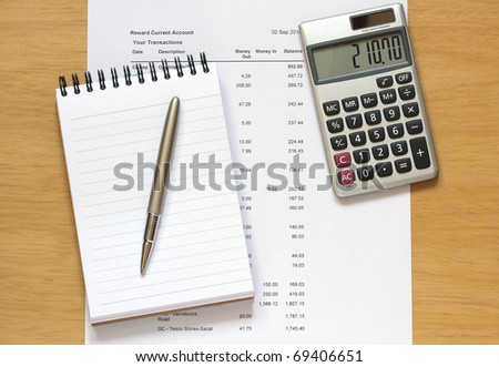 calculator with notebook and pen on a page of financial figures on a wooden desk