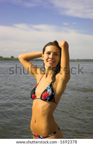 Beautiful girl in swimsuit on riverside at solar day