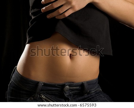 girls belly, jeans and hand isolated on black