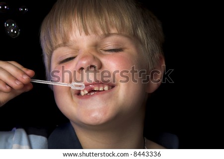 boy playing with soap bubbles isolated on black