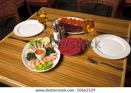 restaurant interior - laying table with white wine and shrimps