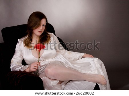 Gorgeous woman in armchair holding the flower