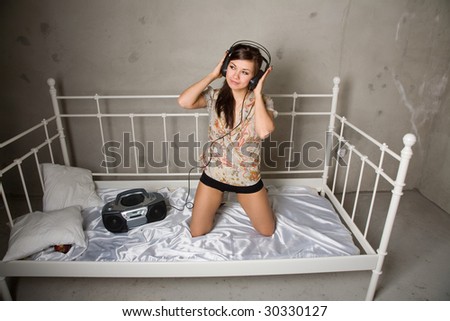 young beauty girl listening music sitting on the bed