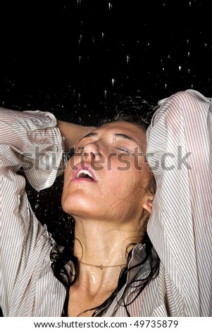 Young girl in shirt in rain isolated on black background