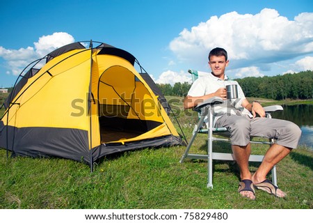 happy man sitting in armchair near yellow tent