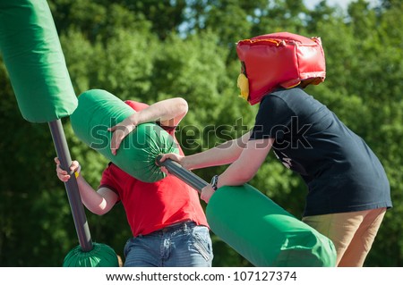 two small children in a hand-to-hand combat game with foam clubs