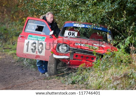 ALDERSHOT, UK - NOVEMBER 3, 2012: Safety crew helping to tow a wrecked Ford Escort out of the undergrowth on the Pavillion stage of the MSA Tempest Rally near Aldershot, UK on November 3, 2012