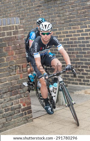 CAMBERLEY, UK - SEPTEMBER 13: British sporting legend, Mark Cavendish cycling on a pedestrian side-walk before the start of a Tour of Britain stage in Camberley, UK - September 13, 2014