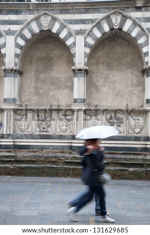 Exterior Facade of Santa Maria Novella Church; Florence; Italy with Couple Walking with Umbrellas