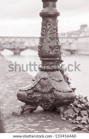 Lamppost Base and the Ponte Vecchio Bridge with River Arno, Florence, Italy in Black and White Sepia Tone