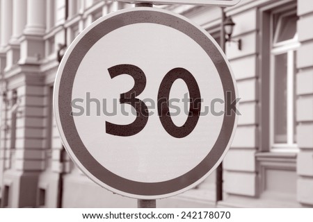Thirty Kilometer Per Hour Speed Limit Sign in Urban Setting in Black and White Sepia Tone