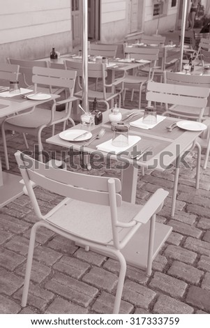 Cafe Tables and Chairs on Cobbled Stones in Black and White Sepia Tone