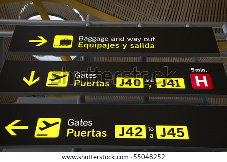 Airport gate and baggage sign in English and Spanish in modern airport