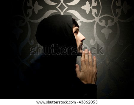 Young caucasian man with hood and beard praying