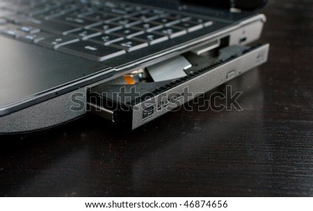 DVD Rom of a black laptop on a wooden table