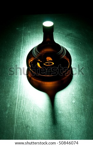 Amber bottle in green spotlight on the floor