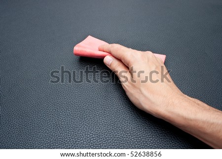 Hand wiping a leather sofa