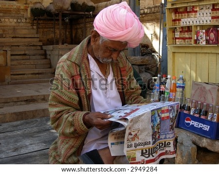 Man with pink turban reading newspaper