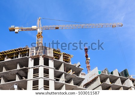 Buildings under construction with cranes on blue sky