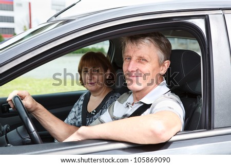 Mature happy Caucasian couple sitting in domestic car and smiling