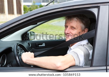 Happy Caucasian senior man fastens safety belt sitting in car on driver seat