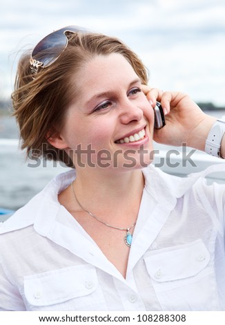 Happy woman in white shirt with sunglasses calling on mobile telephone.