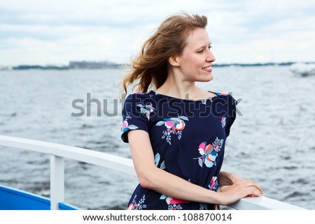 Girl standing on the deck of cruise yacht on wind and looking far away